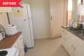 Small kitchen with white cabinets, wooden countertops, a fridge, and a sink with floral curtains.