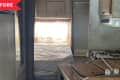 Small RV interior with a kitchenette, stove, wooden cabinets, and a bed with floral curtains.
