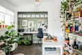 Home office with a desk, black chair, potted plants, bookshelves, and wall art, creating a cozy and organized workspace.