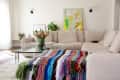 Cozy living room with white walls, tan sectional, and rainbow crocheted blanket at foot of sectional