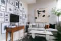 Living room with a gray sofa, abstract wall art, gallery wall of photos, wooden console table, and a potted plant.