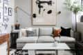 Modern living room with a gray sofa, abstract wall art, black and white cushions, and a white coffee table.