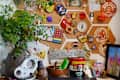 Corkboard with colorful pins and patches, potted plant, and eclectic desk items including a Medaglia D'Oro espresso can.