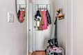 White entryway with coats and jackets hanging, a shoe rack, and small wall hooks