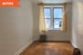 Empty room with parquet flooring, beige walls, a window with sheer curtains, and a small radiator.