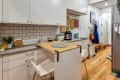 Modern kitchen with white cabinets, subway tile backsplash, wooden floor, and a small dining table with two chairs.