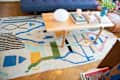 Colorful abstract rug under a wooden coffee table with books, a candle, and a vase of pink flowers.