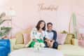 Mother and son sitting on a couch under a pink sign reading "Thankful"
