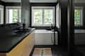Modern bathroom with black walls, large windows, a white bathtub, black fixtures, and a wooden vanity with a black countertop.