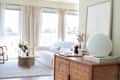 Bright living room with a white sofa, wooden coffee table, and a sideboard with decor items and a framed line drawing.