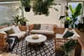 A large living room with wicker furniture and plants hanging overhead