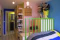 Colorful children's room with green bed frame, stuffed panda, shoe shelves, and a "SCULPTURE" bag on the wall.