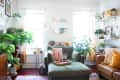 A bright living room with burgundy floors, a green chair, and lots of green plants
