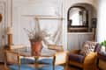 Dining area with glass table, wicker chairs, potted plant centerpiece, and cozy seating nook with checkered pillow.