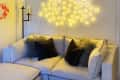 Cozy living room with a cream sectional sofa, fluffy pillows, abstract wall art, and a glowing circular light fixture.