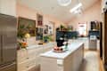 Spacious kitchen with white island, blue tile backsplash, paintings, and fruit bowl on counter.