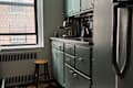 Dark green painted kitchen cabinets with gold knobs.