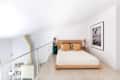 Minimalist white loft bedroom with wood platform bed