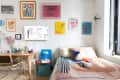 Colorful artwork hung on bedroom wall in studio apartment with colorful neatly made bed.