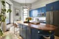 Blue cabinets in gray-painted kitchen with multi-armed pendant light hung over island.