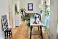 White painted living room with baby blue chairs around a table and a green sofa flanked by plants