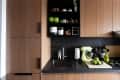 Kitchen with wood cabinets, black tile and countertops, green accents