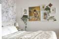 Cozy bedroom with floral wallpaper, white bedding, and framed art on the wall, accented by green plants.
