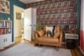 Room with patterned wallpaper, tan leather chair, bookshelves, area rug