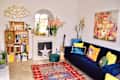 Blue velvet sofa topped with colorful pillows in colorful living room.
