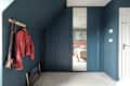 dark teal walls, wardrobe, wooden coat hanger, thin tall doors, white carpet, angled wall