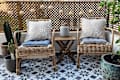 patio with straw/wicker/cane chairs with blue and white cushions, round string lights, plants, black and white star tile, wood privacy rail/screen