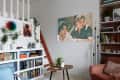 living room with blue loveseat, white walls, lots of plants, built-in shelves, art/photography on walls, wood art details