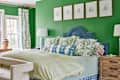 Blue velvet upholstered bed in Kelly green bedroom. Drawings of kids portraits are mounted above bed.