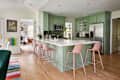 Pink stools surround green bar area in kitchen with white quartz countertops.