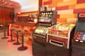 bar with classic records on display behind bar, red, orange, cream tiles, stripes on wall, slot machine, other game machines