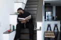 A man holding a book laughing on a black staircase