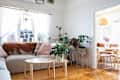 White living room with grey couch, wooden coffee table and plants in planters.