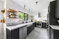 Black cabinets and marble countertops in light filled kitchen.