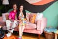 Couple sitting on pink sofa in colorful living room.