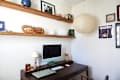 Wooden shelves next to paper lantern above dark desk with computer.