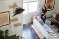 Dweller in living room gets attention of cat on shelf beneath nook at stair landing.