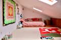 Colorful artwork on wall and floor of bedroom with bed with red striped bedding.