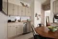 Beige cabinetry in kitchen with white tile backsplash and off-white walls.