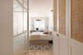 Neatly made bed in neutral toned apartment.