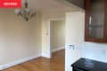 Bare dining room with hanging light fixture and corner of kitchen cabinets