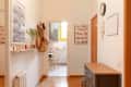 White entryway with hanging bags and baskets, floating shelf, and view into kitchen