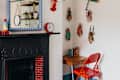 Small desk and red chair next to fireplace with blue bobbin mirror