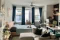 A dog sits in a bed in a studio apartment with large windows.