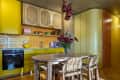 Yellow kitchen with fluted wood cabinets, parquet floor, window bar and dining table