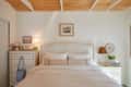 A bed flanked by a dresser and night with a picture on a dresser.